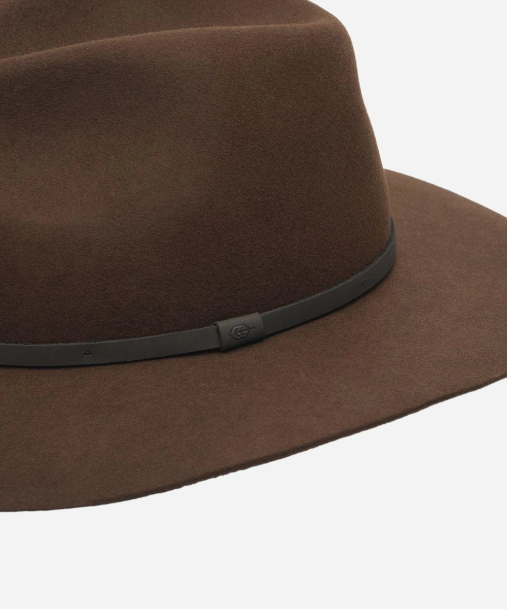 Close up of the hand folding the durable Indy brown felt hat to demonstrate its premium packable design