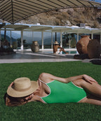 Female model lounging by a luxury resort pool wearing the Gentry natural raffia boater hat LBORA