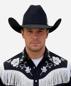 Masculine persona in an embroidered shirt wearing the black Magnate hat