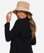 Studio portrait of a female model showcasing the downward sloping brim of the Solstice black woven straw bucket hat